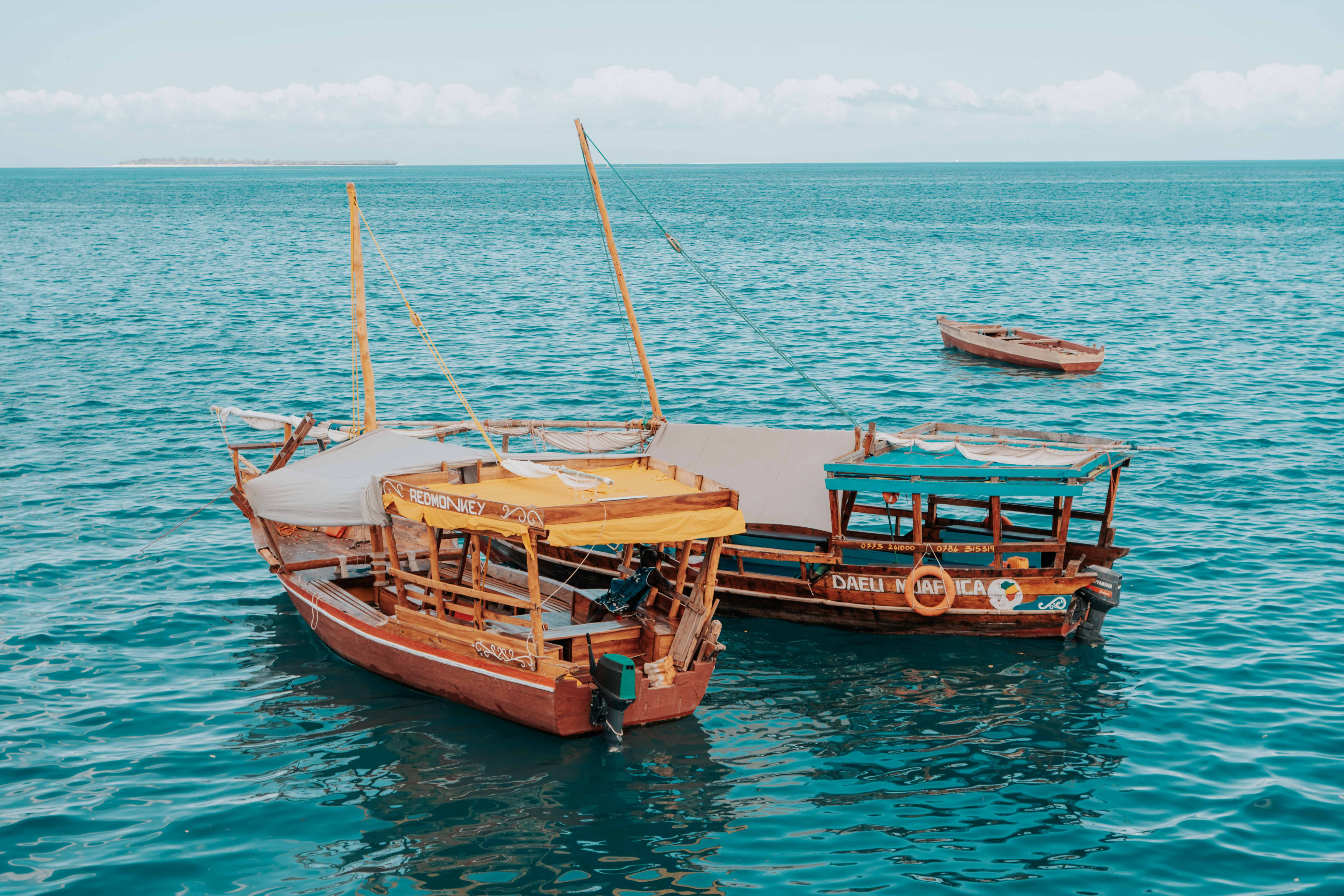 Traditional dhows sail across turquoise coastal waters.