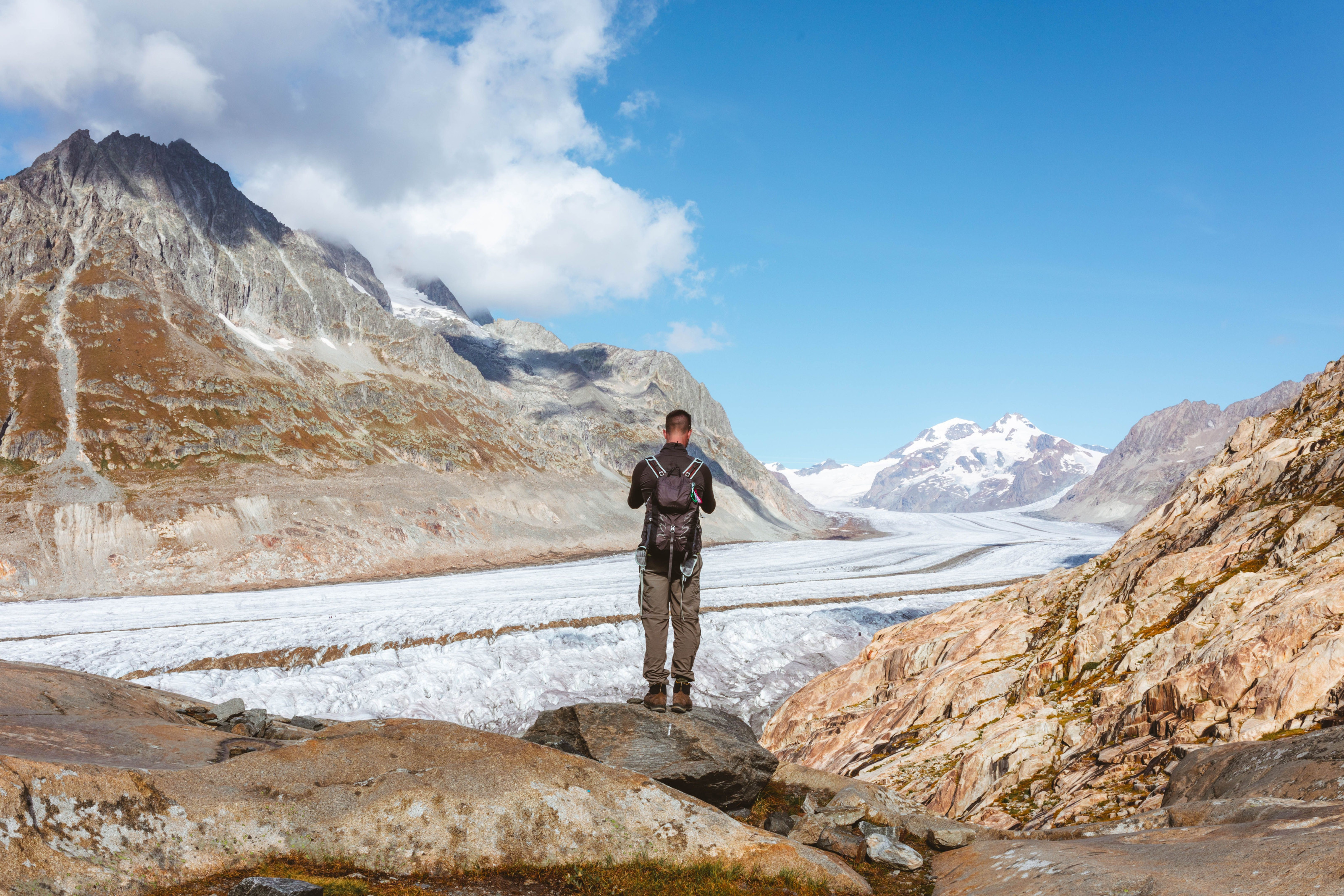 A hiker pausing to take in a sweeping glacier and mountain view.