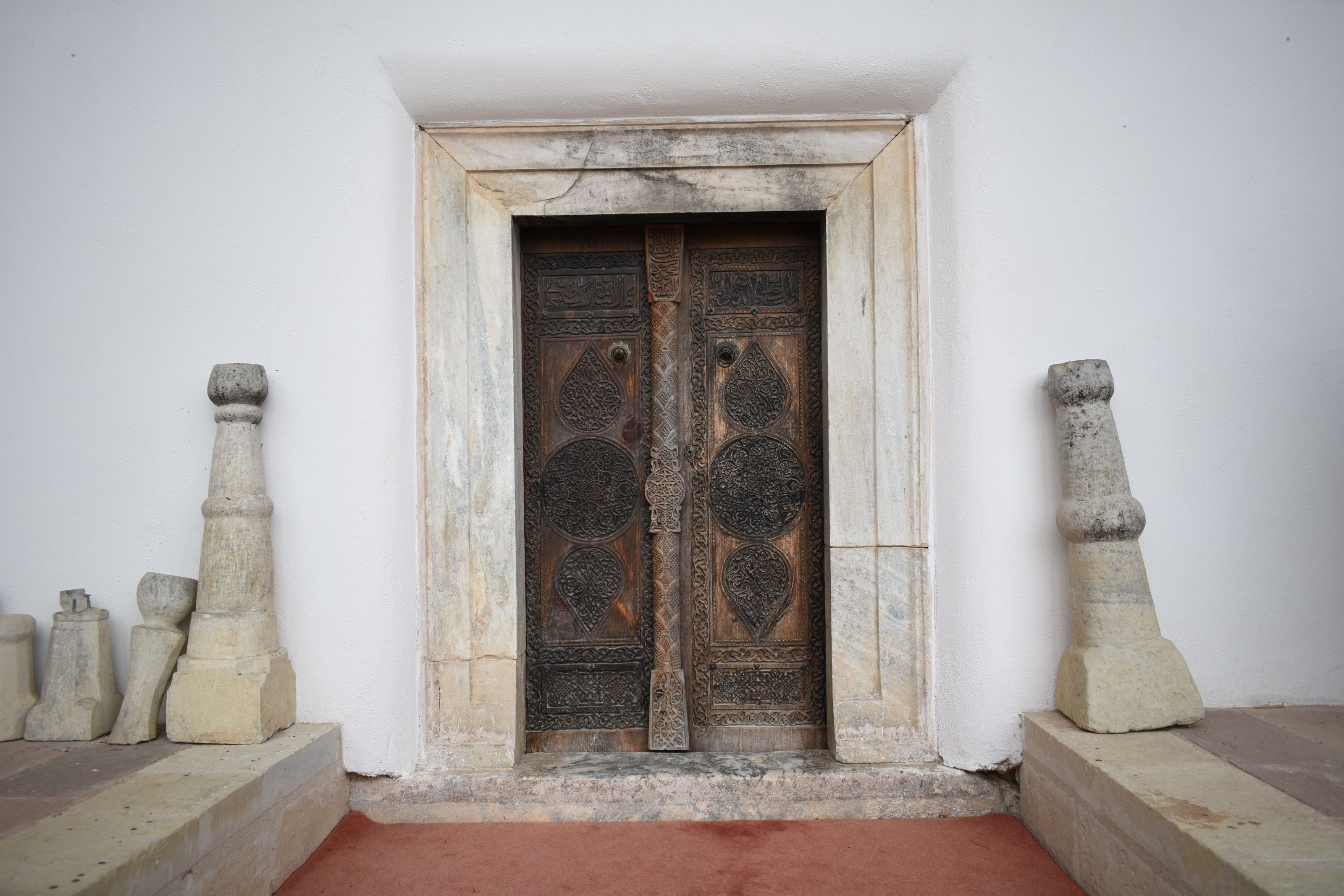 An intricately carved antique wooden door set into a historic stone facade.