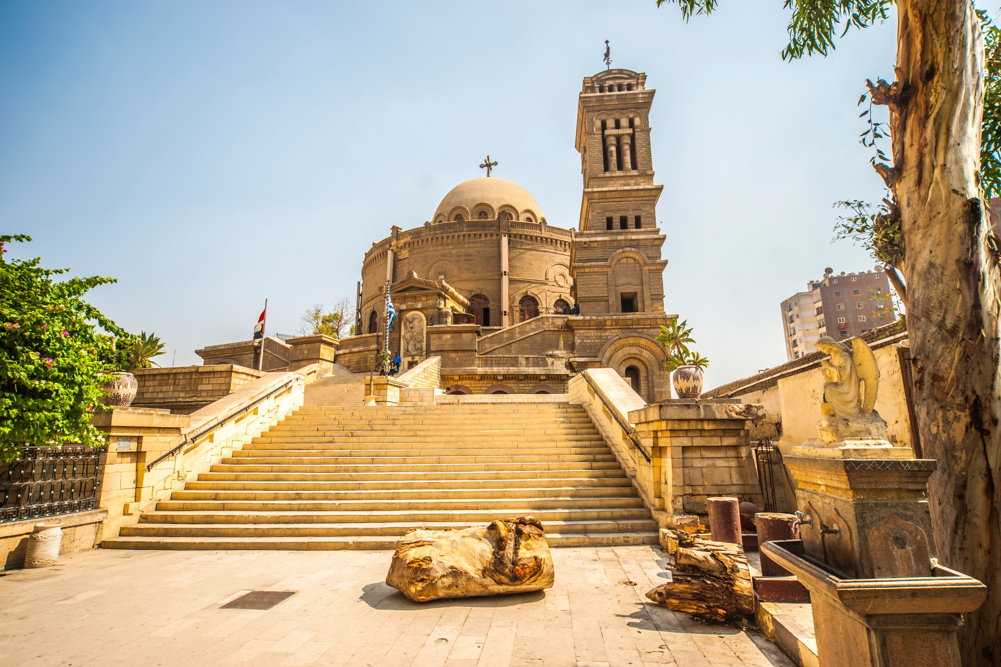 A grand stone church tower rises above a wide staircase, its entrance framed by pale golden masonry.