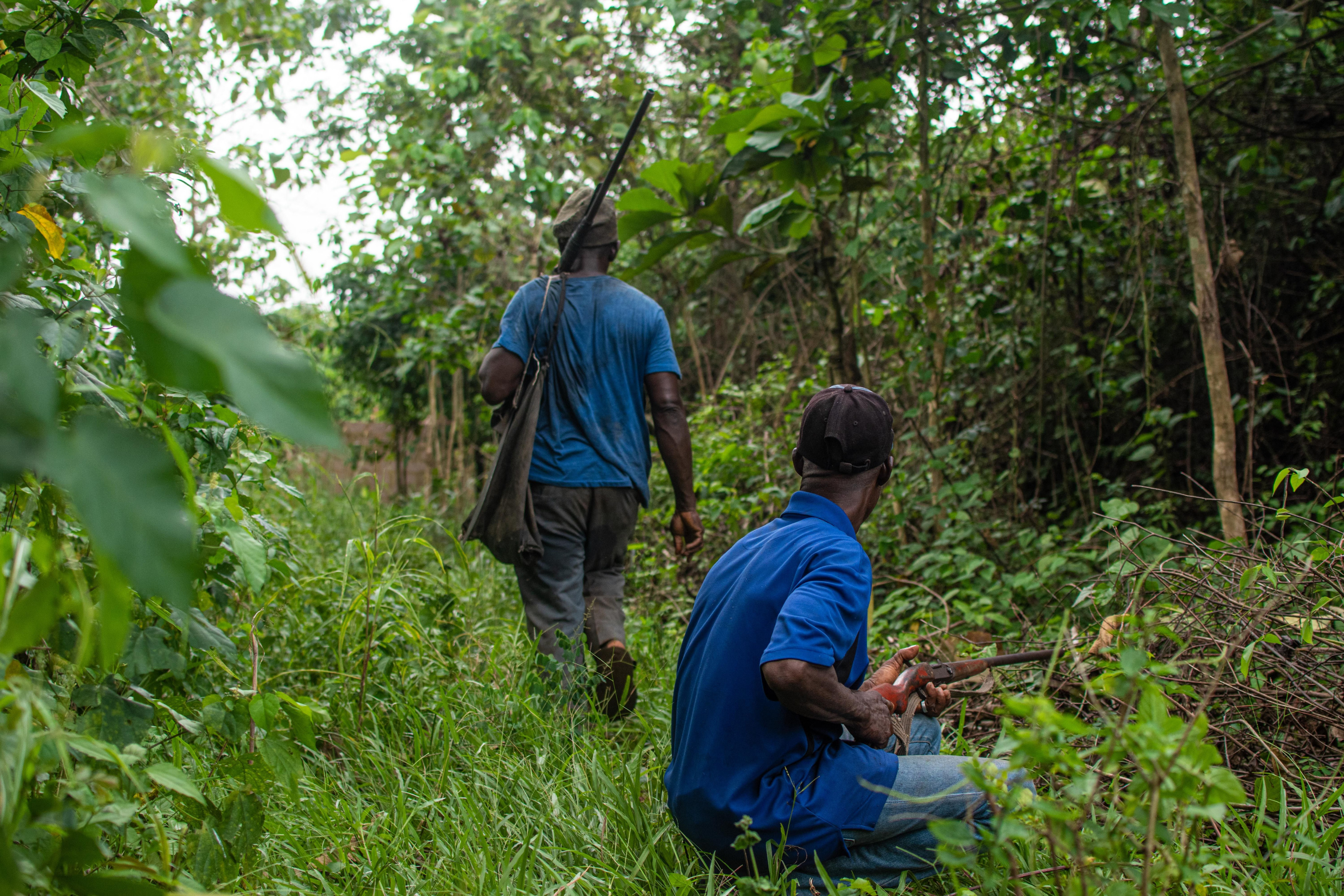 Two armed guides walking through dense bush on a walking safari.