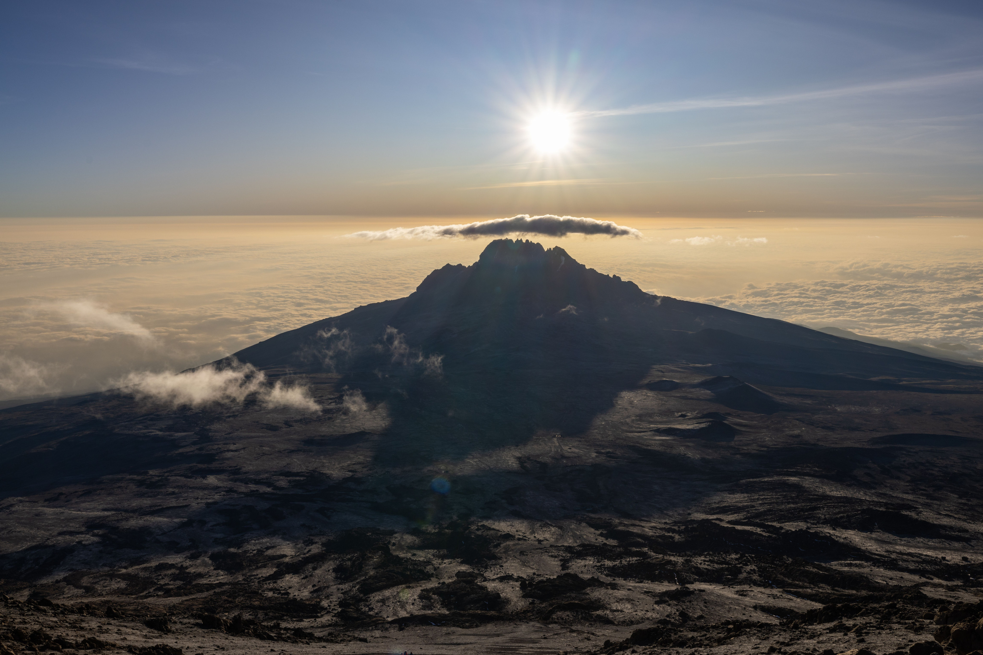 The sun rises behind the silhouette of Mount Kilimanjaro's summit.