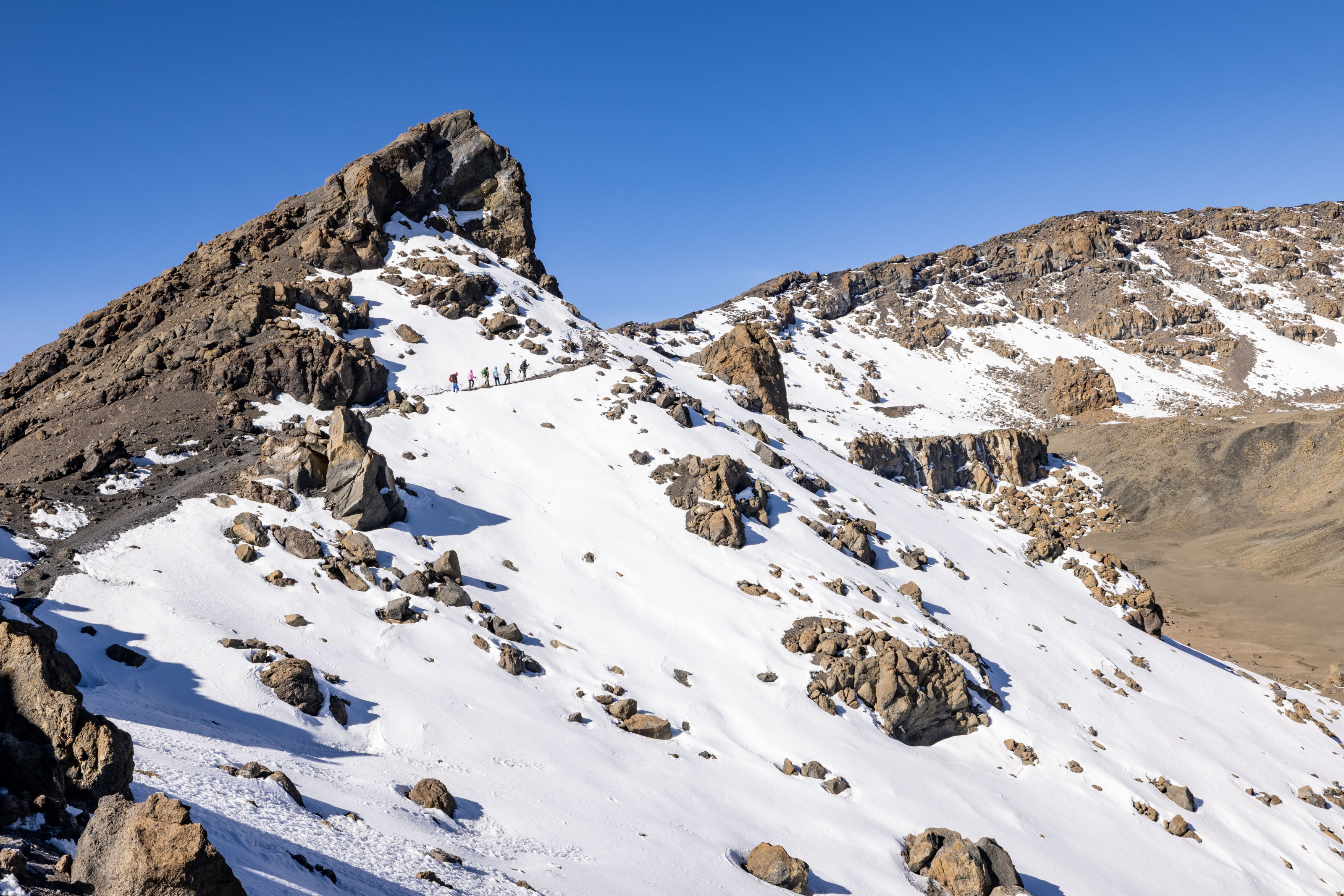 A group of climbers ascends the snowy upper slopes near Kilimanjaro's peak.