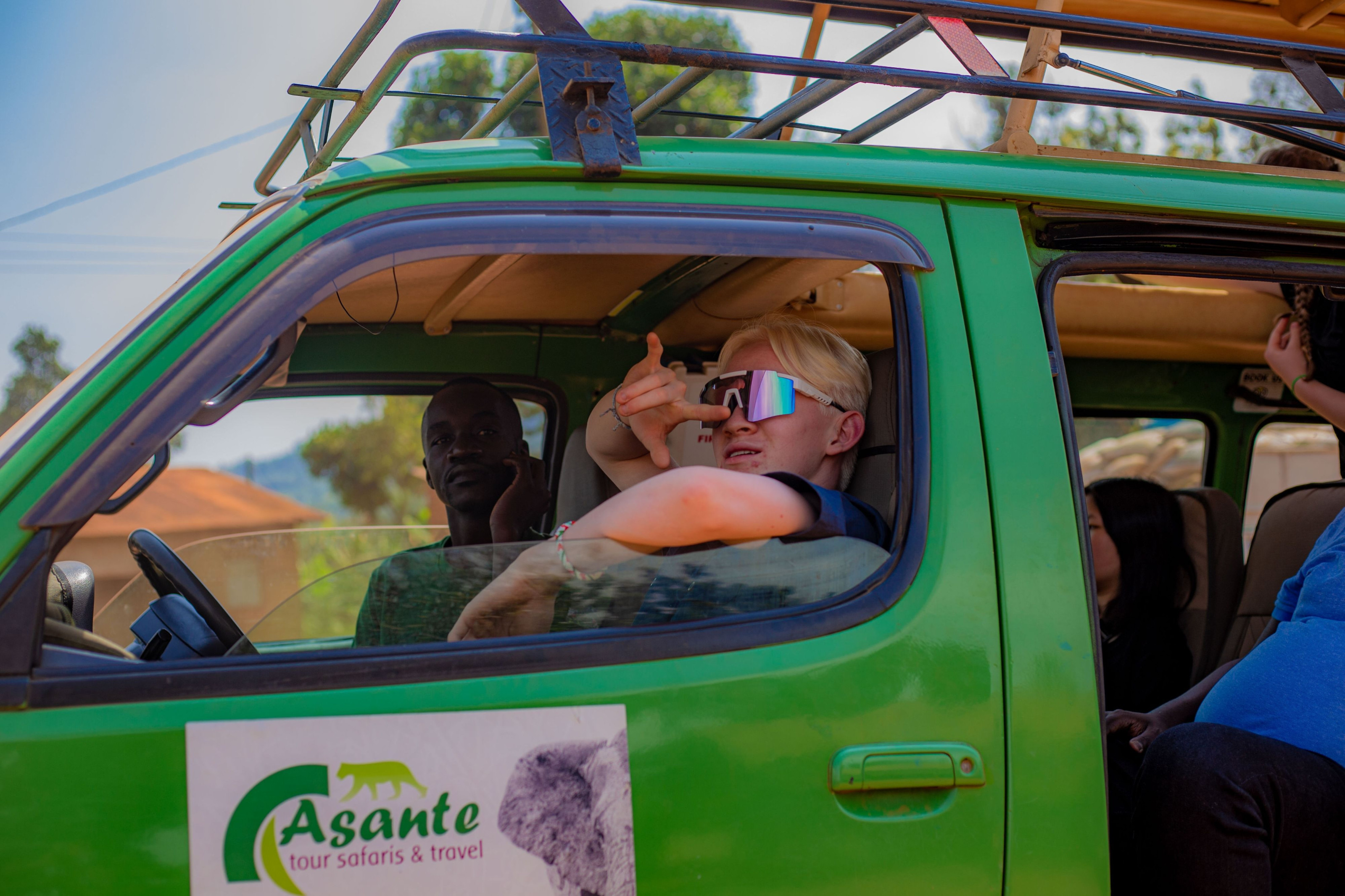 Travellers ride in an open safari vehicle through Uganda's green countryside.