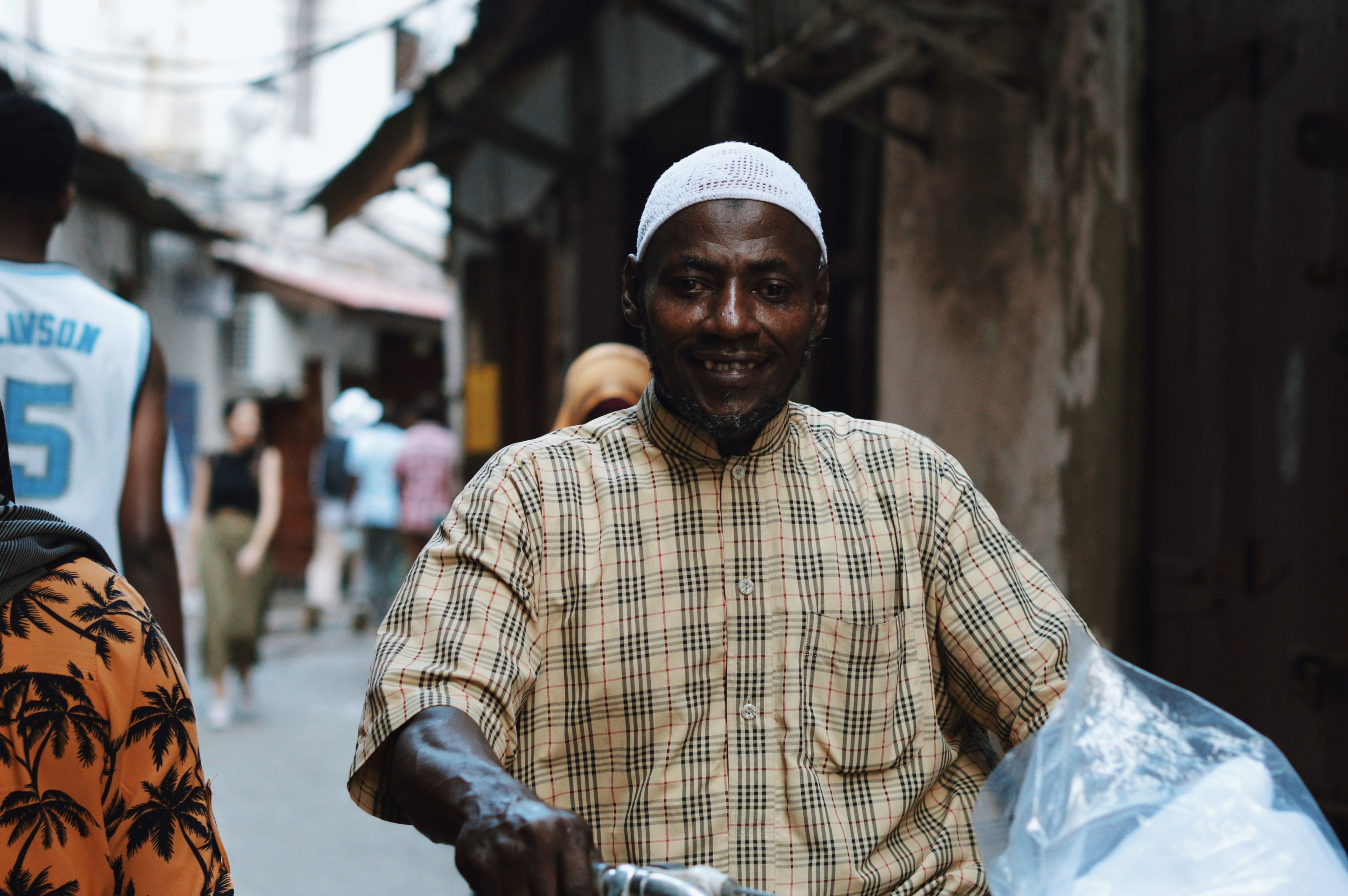 A man rides a bicycle through the bustling historic streets of Stone Town, Zanzibar.
