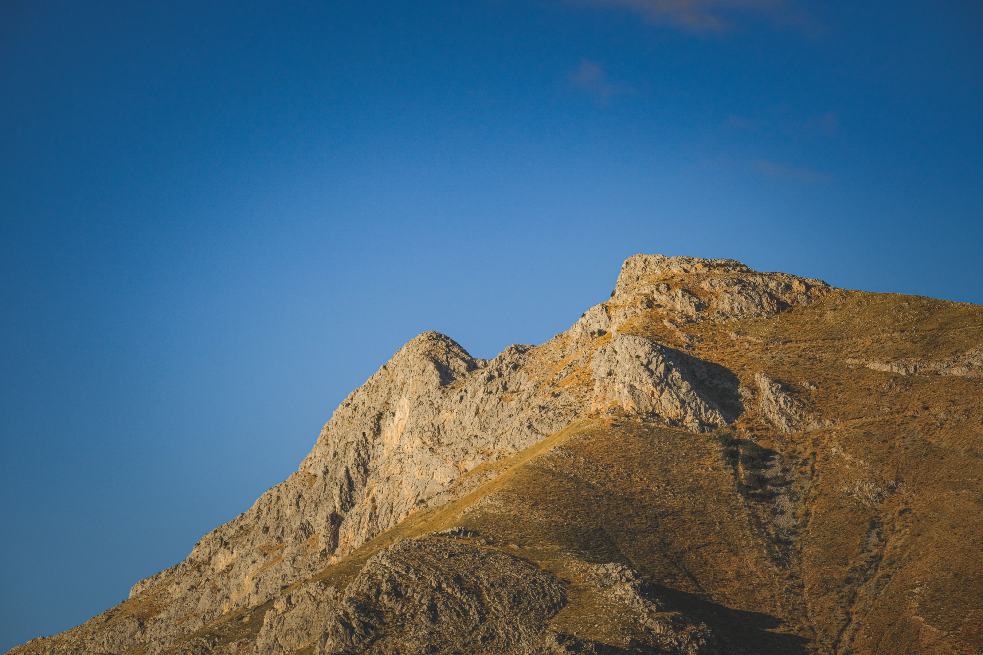 A jagged rock peak stands sharply outlined against a clear blue highland sky.