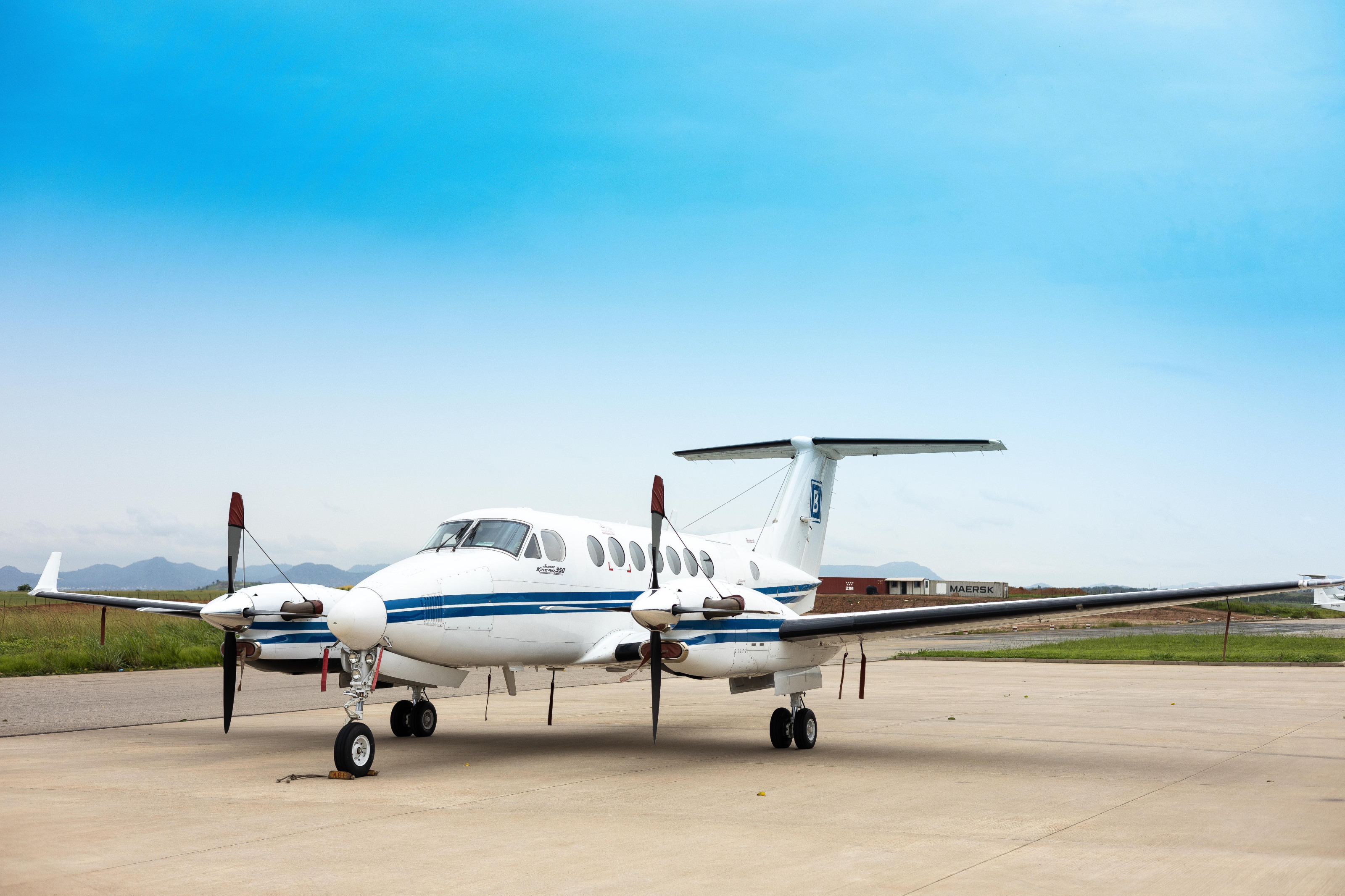 A small charter plane waits on a dirt airstrip beneath an open blue sky.