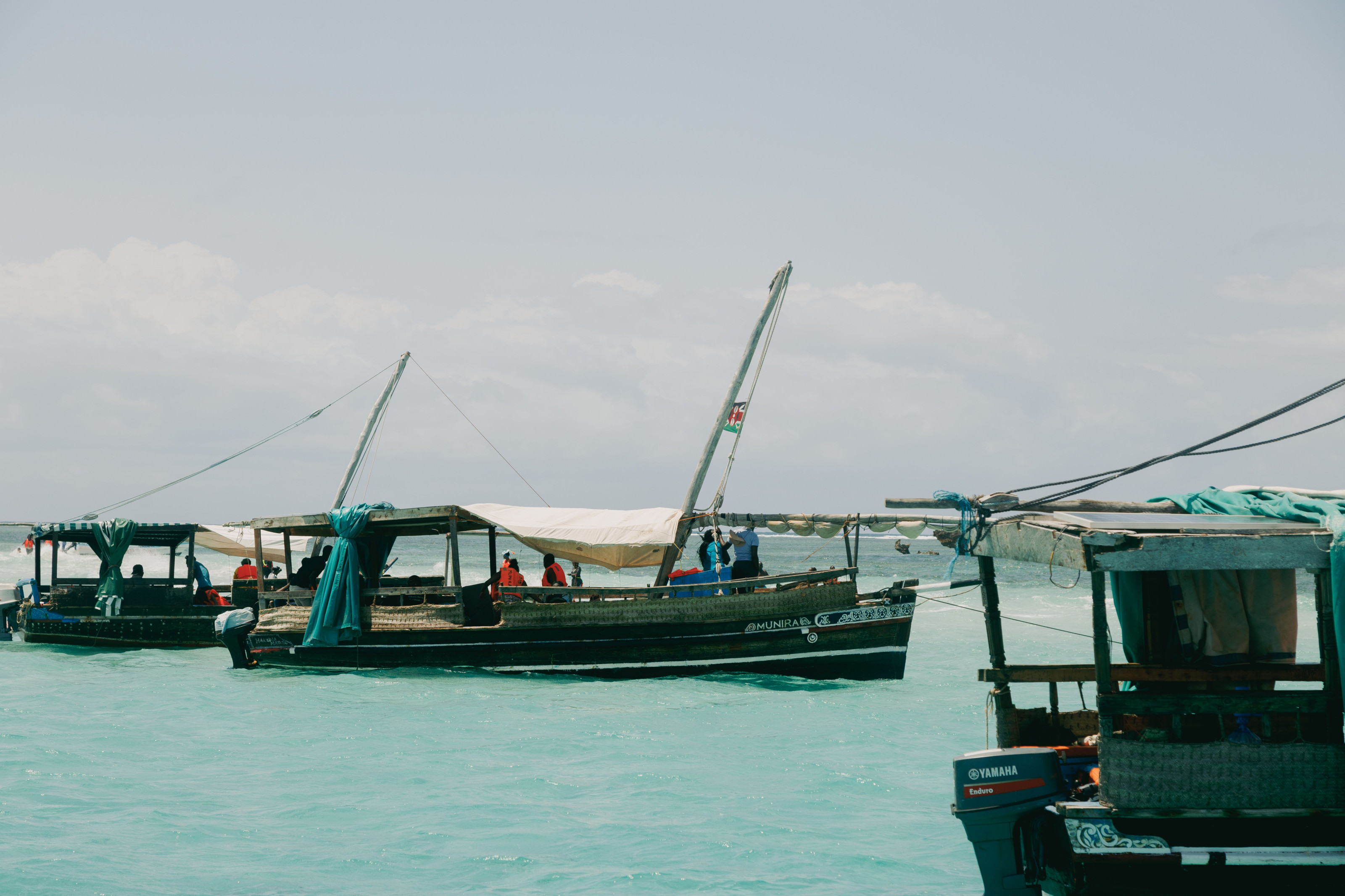 Traditional wooden fishing boats rest along a sunlit coastal harbor.