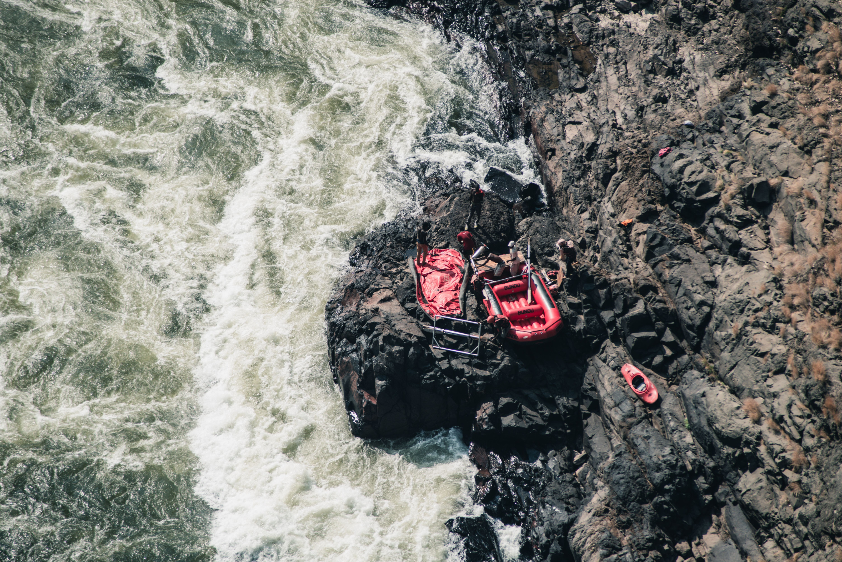 Rafting paddles and safety gear lie ready on a rocky riverbank before launch.
