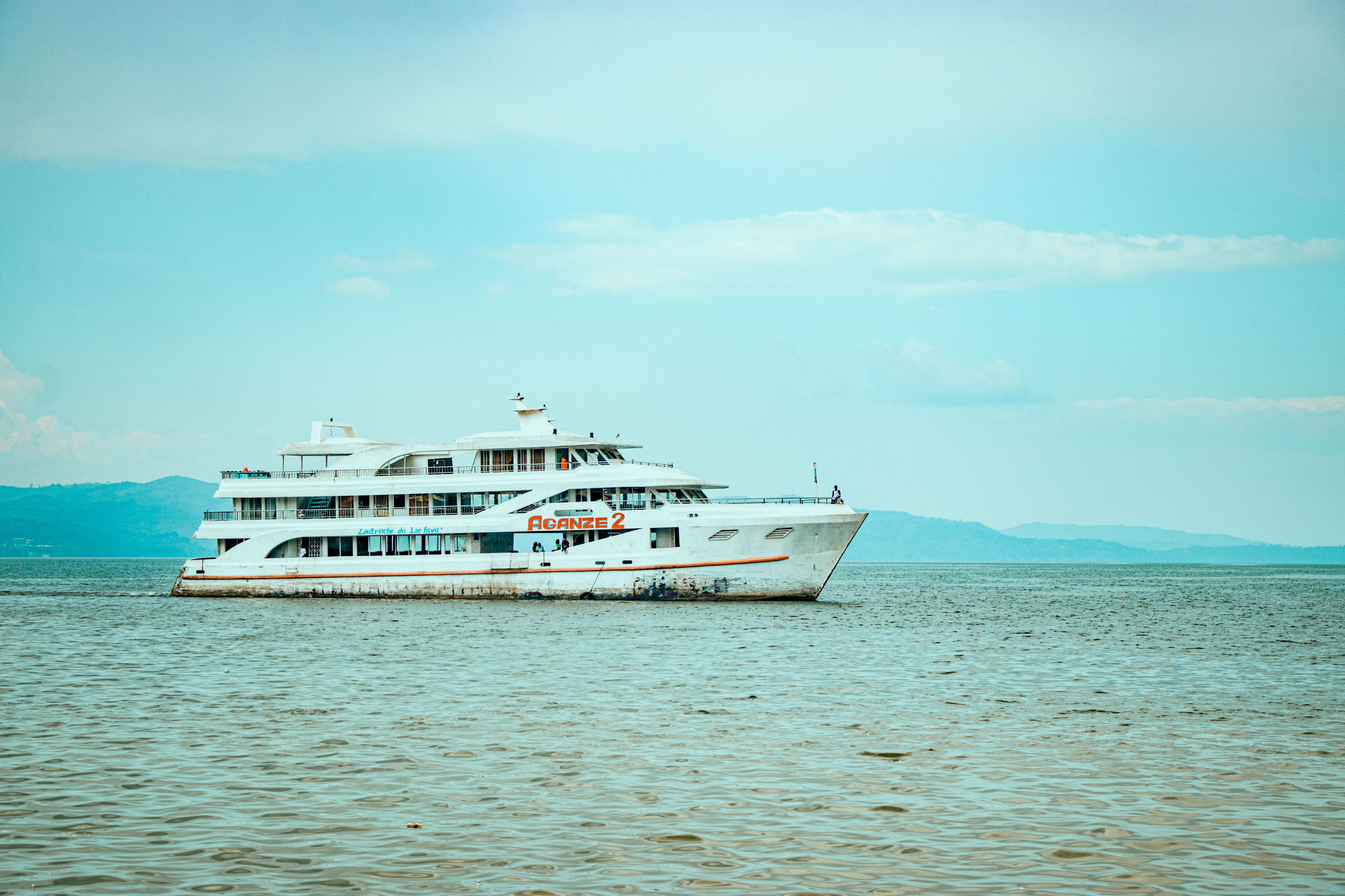 A boat rests on the calm turquoise waters of Lake Kivu framed by green hillsides.