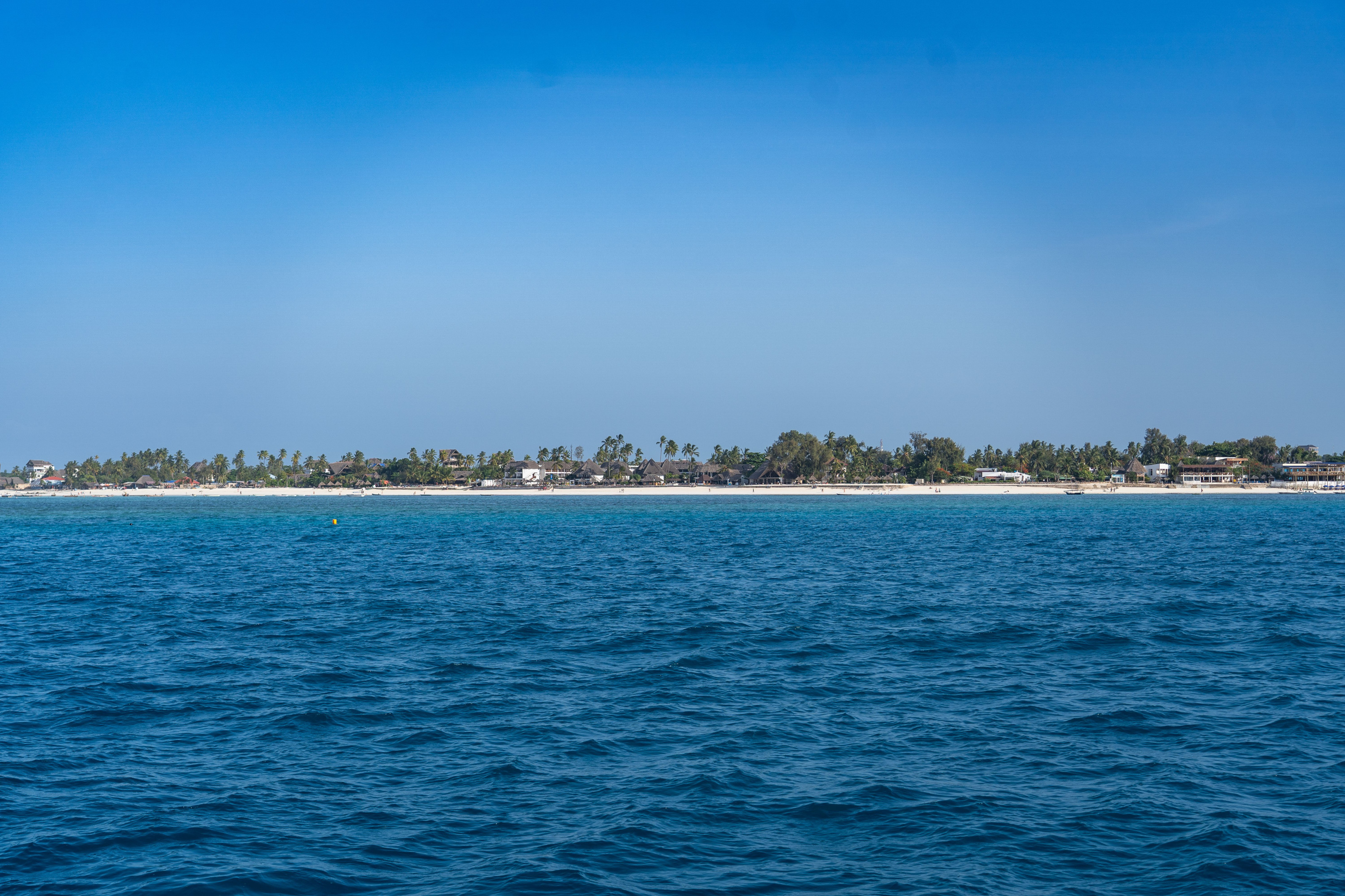 Palm-fringed white sand meets brilliant turquoise water along Zanzibar's coastline.