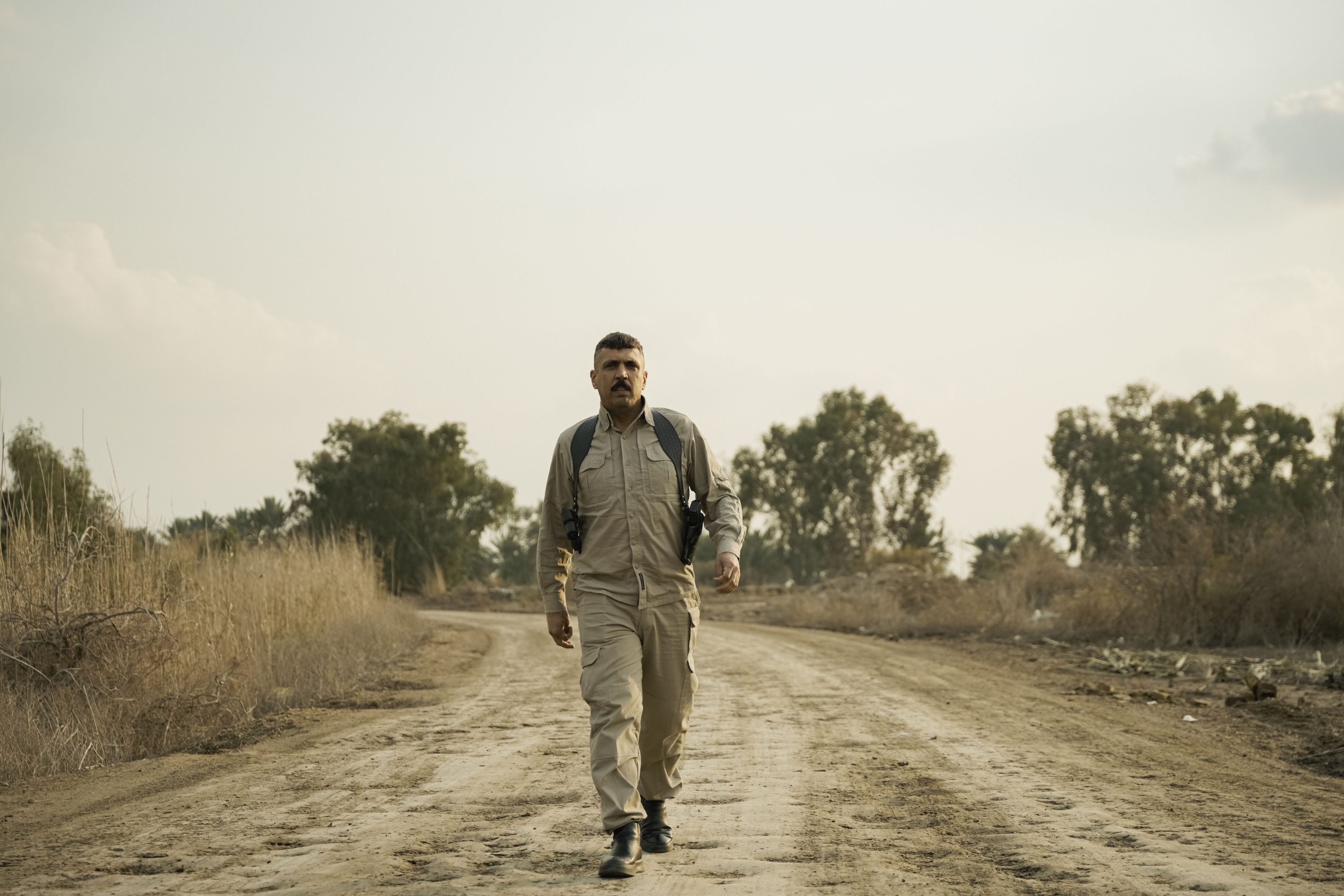 A lone walker with a backpack following a dry rural path.