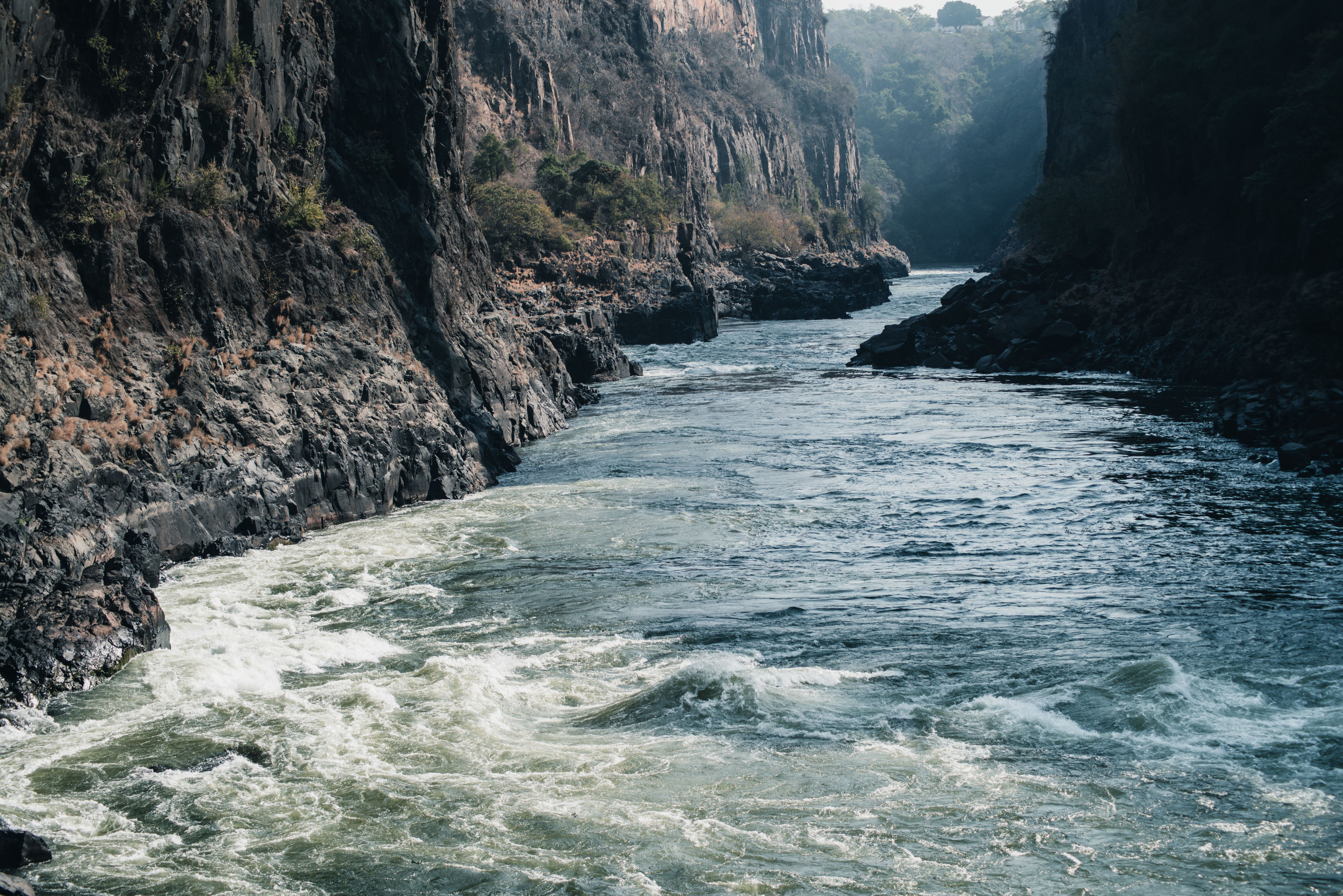 A river forces its way through a dramatic rocky gorge, carving a path between steep cliffs.