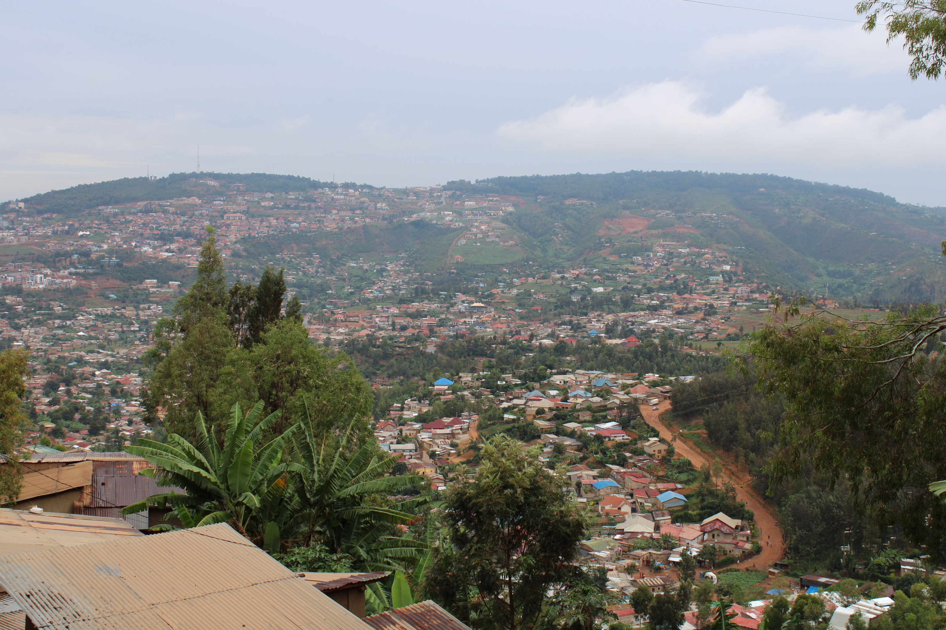 Rooftops and greenery spread across rolling hills seen from above.
