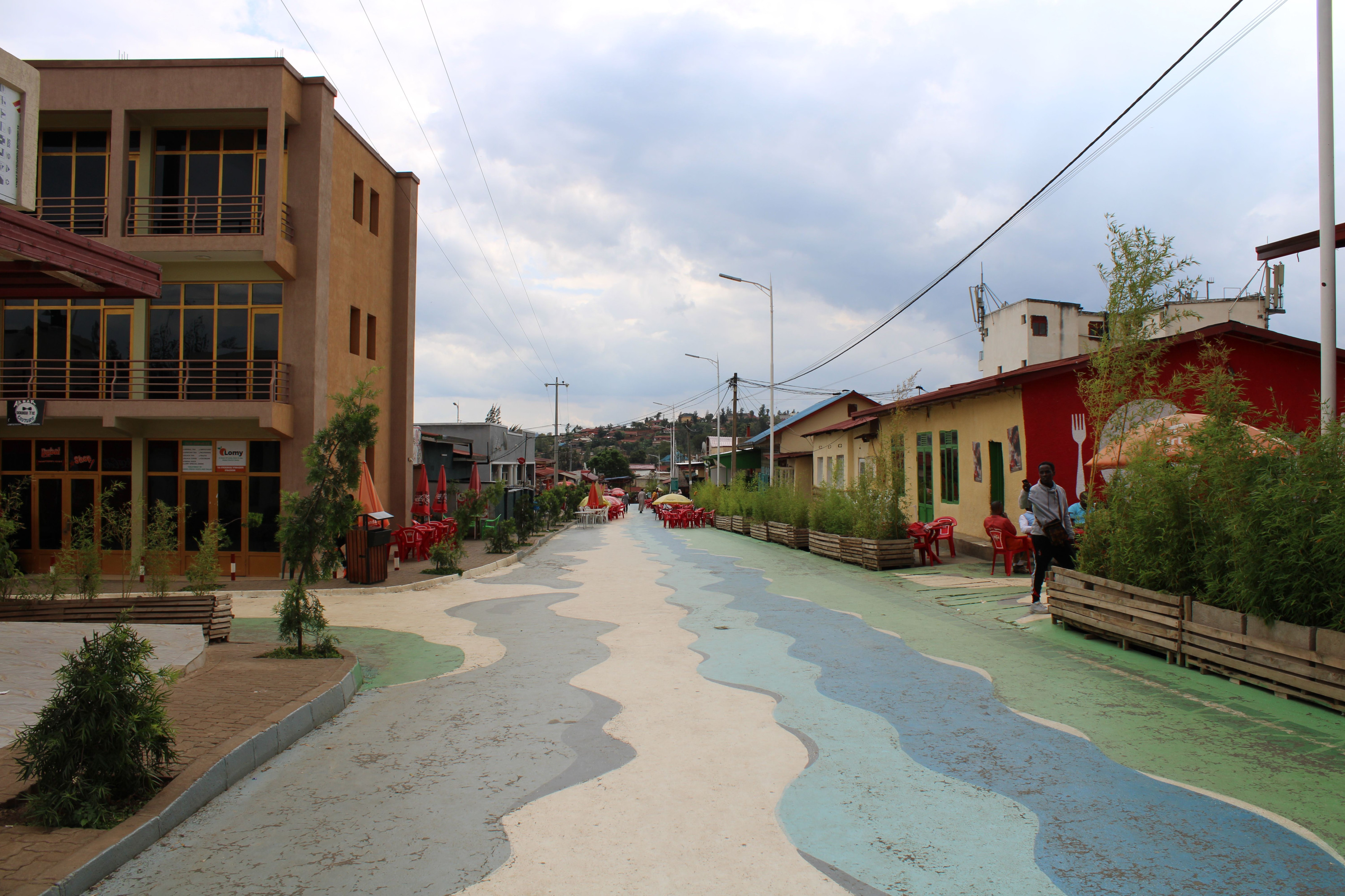 A vibrant street scene in Kigali's Nyamirambo neighborhood, with colorful patterned buildings.