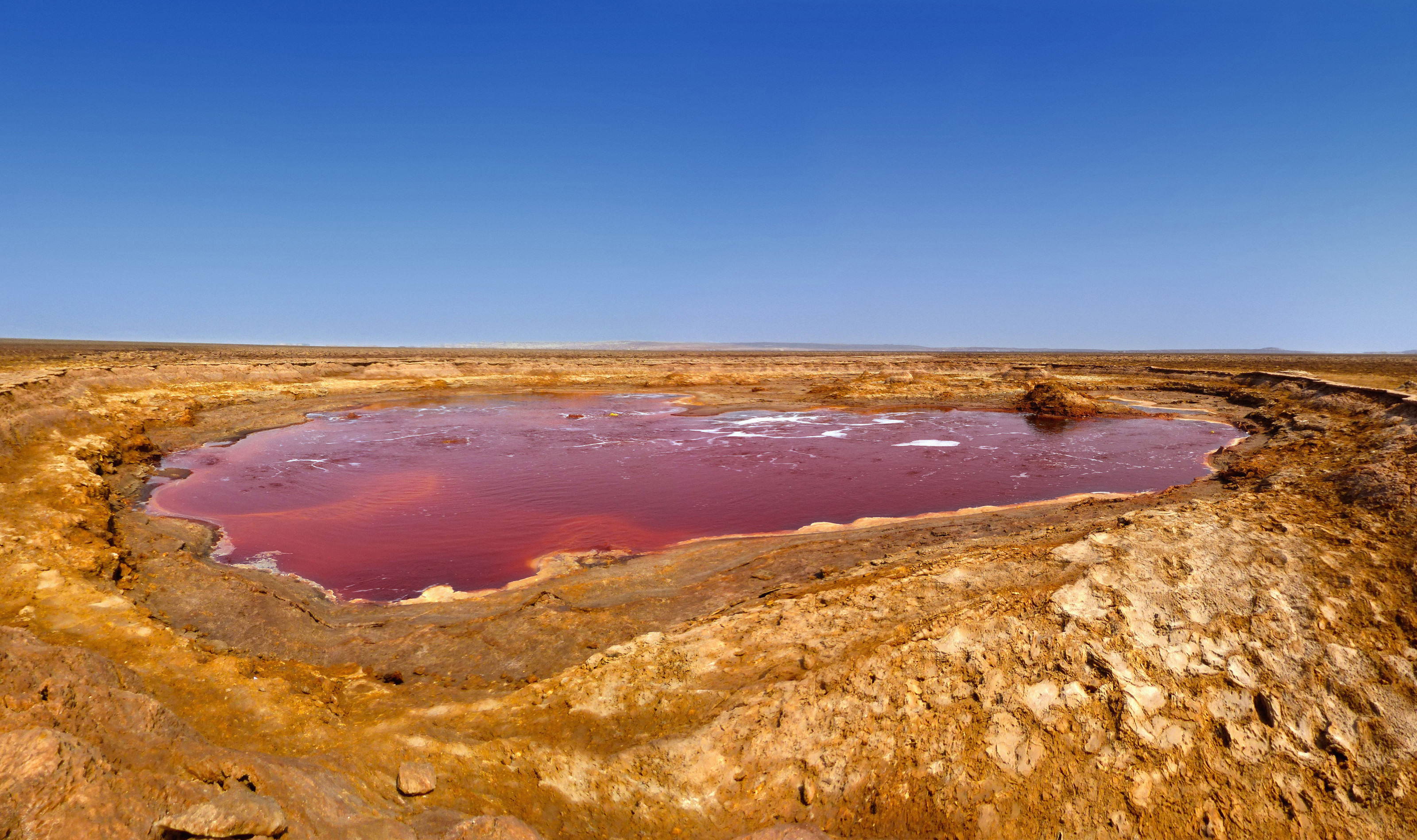 Vivid red and orange mineral pools spread across the otherworldly floor of the Danakil Depression.