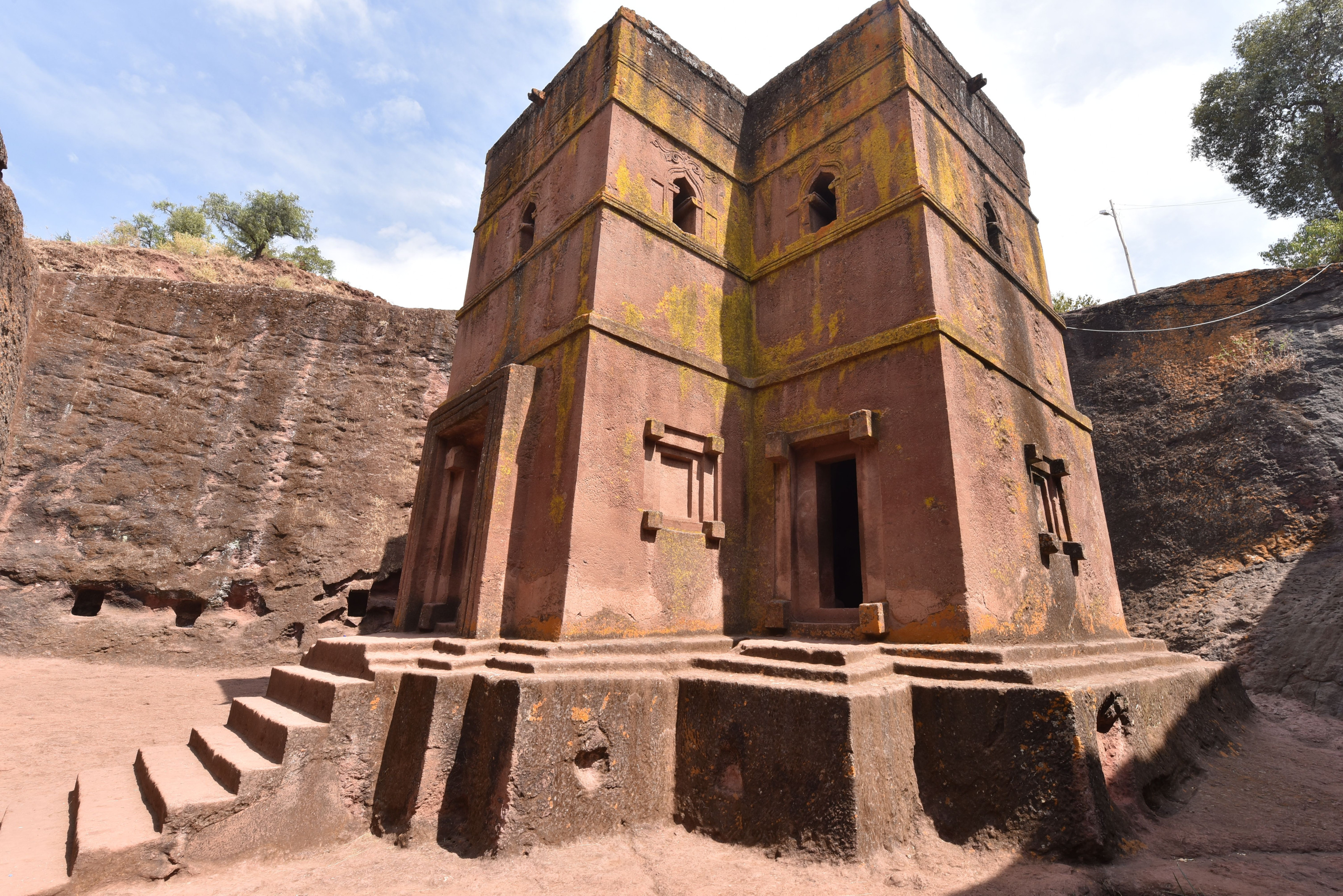 A ground-level view of the weathered stone facade and narrow windows of one of Lalibela's rock-hewn churches.