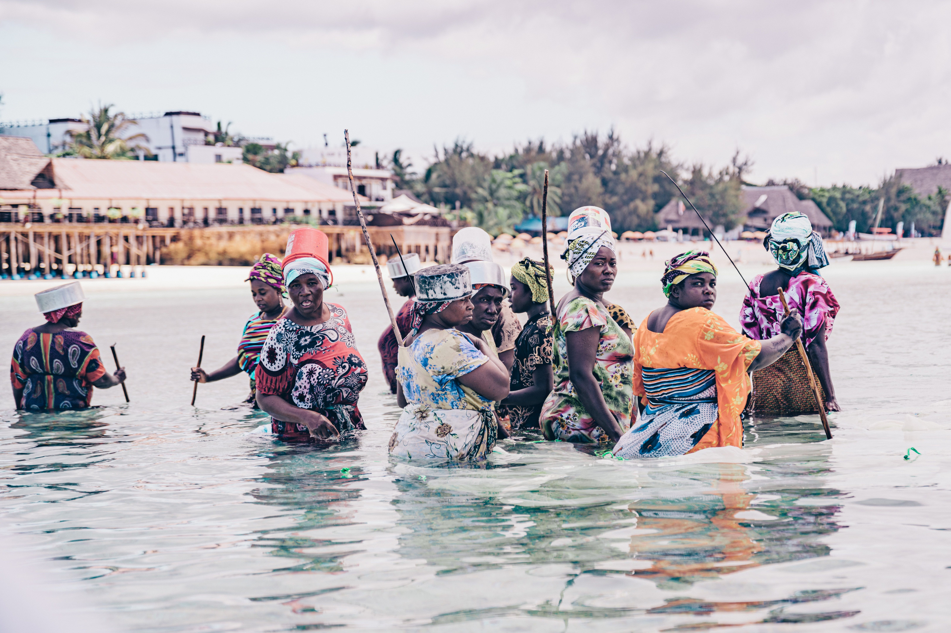 A group of local women wading through shallow water tending their seaweed farms.