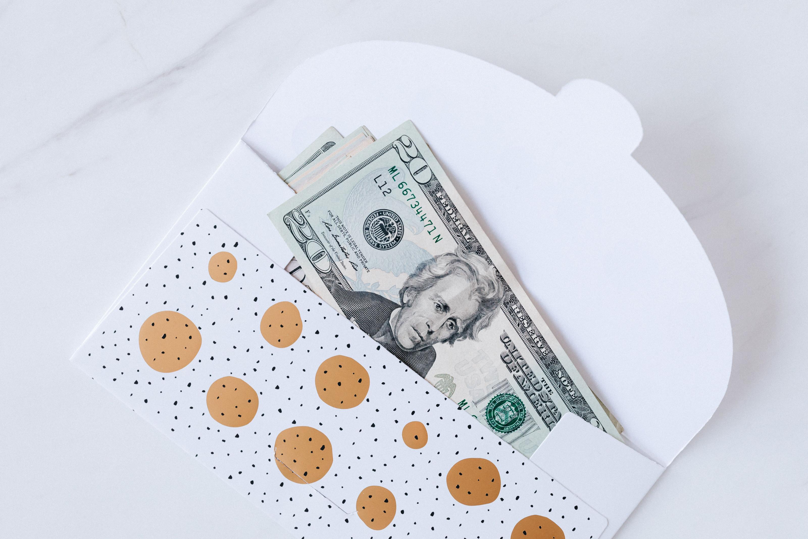 A neat pile of US dollar bills laid inside an open envelope on a plain surface.