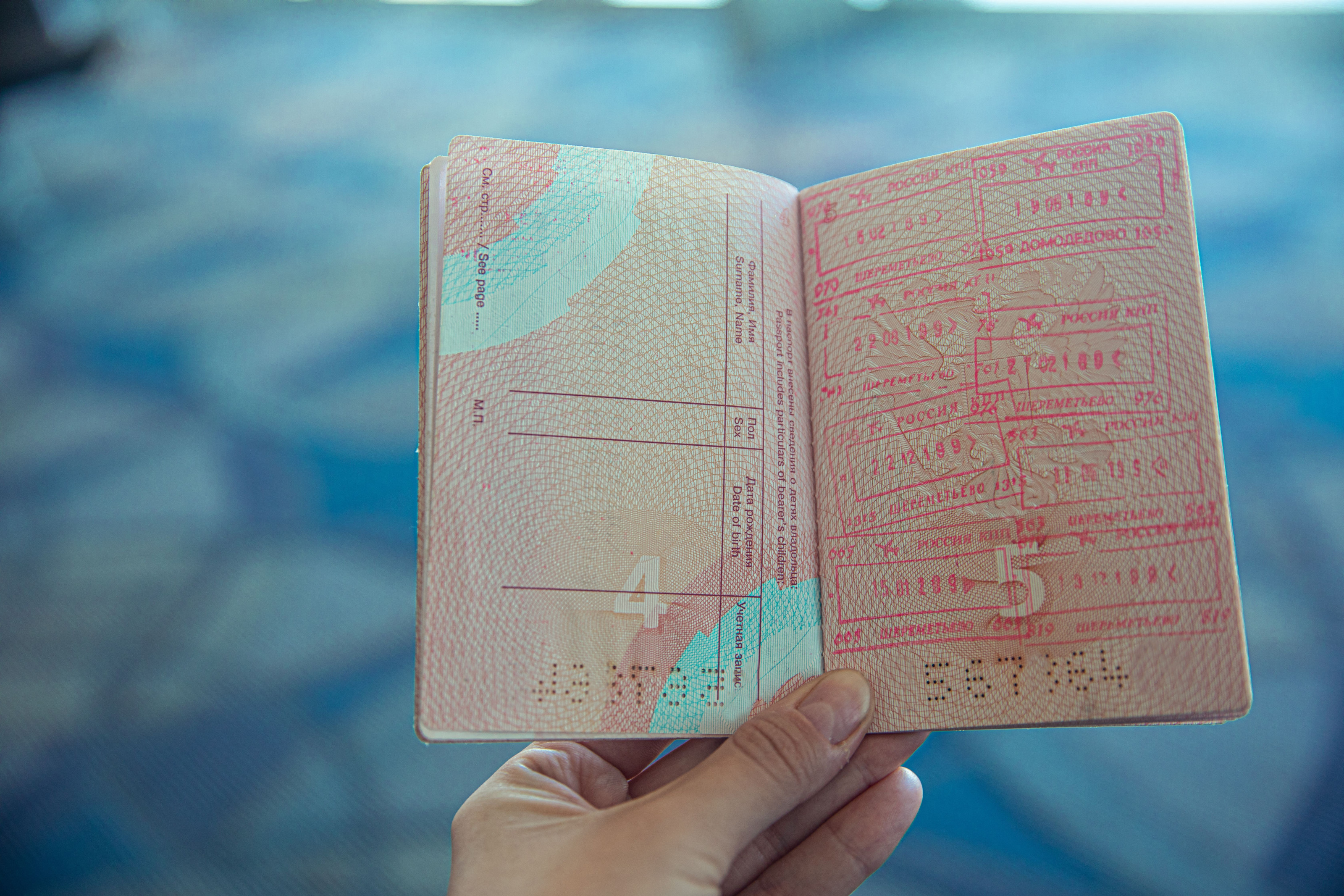 An open passport lies on a desk, its pages covered in colourful entry and exit stamps from past journeys.