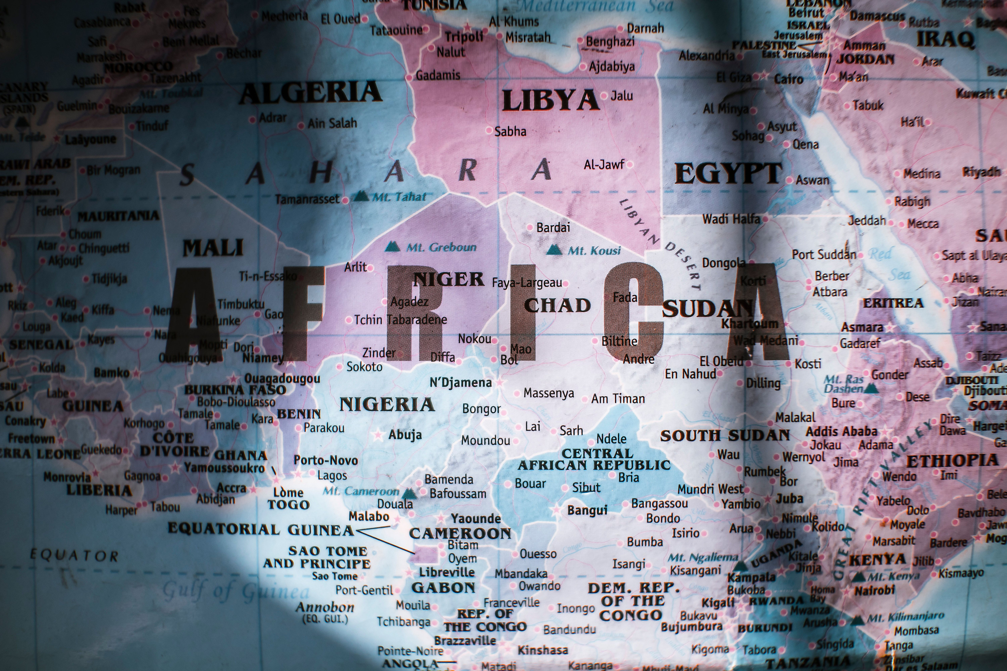 A close-up view of a physical map of Africa showing country borders and coastline in warm sunlight.
