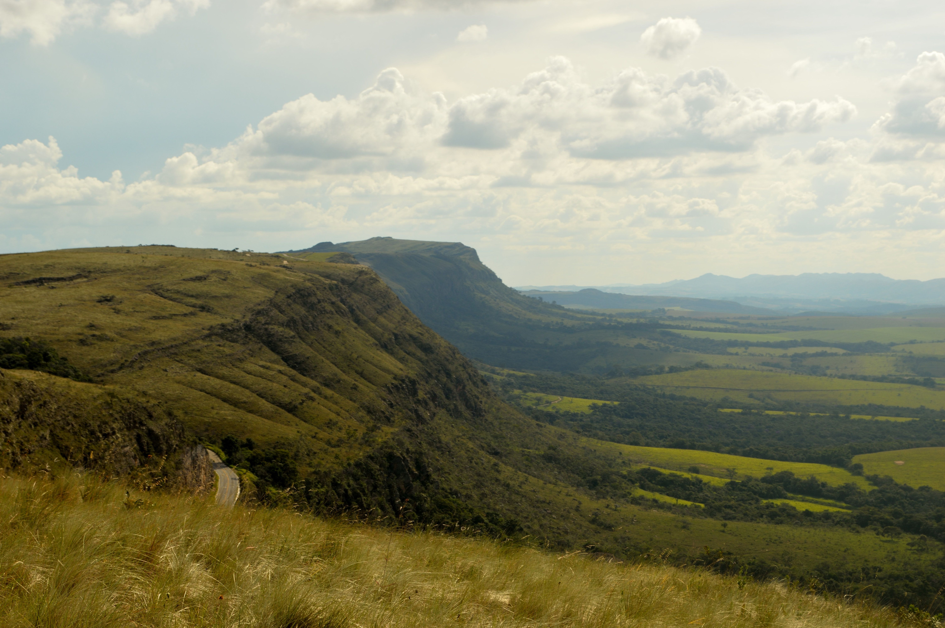 Rolling highland valleys stretch toward the horizon under a wide, cloud-streaked sky.