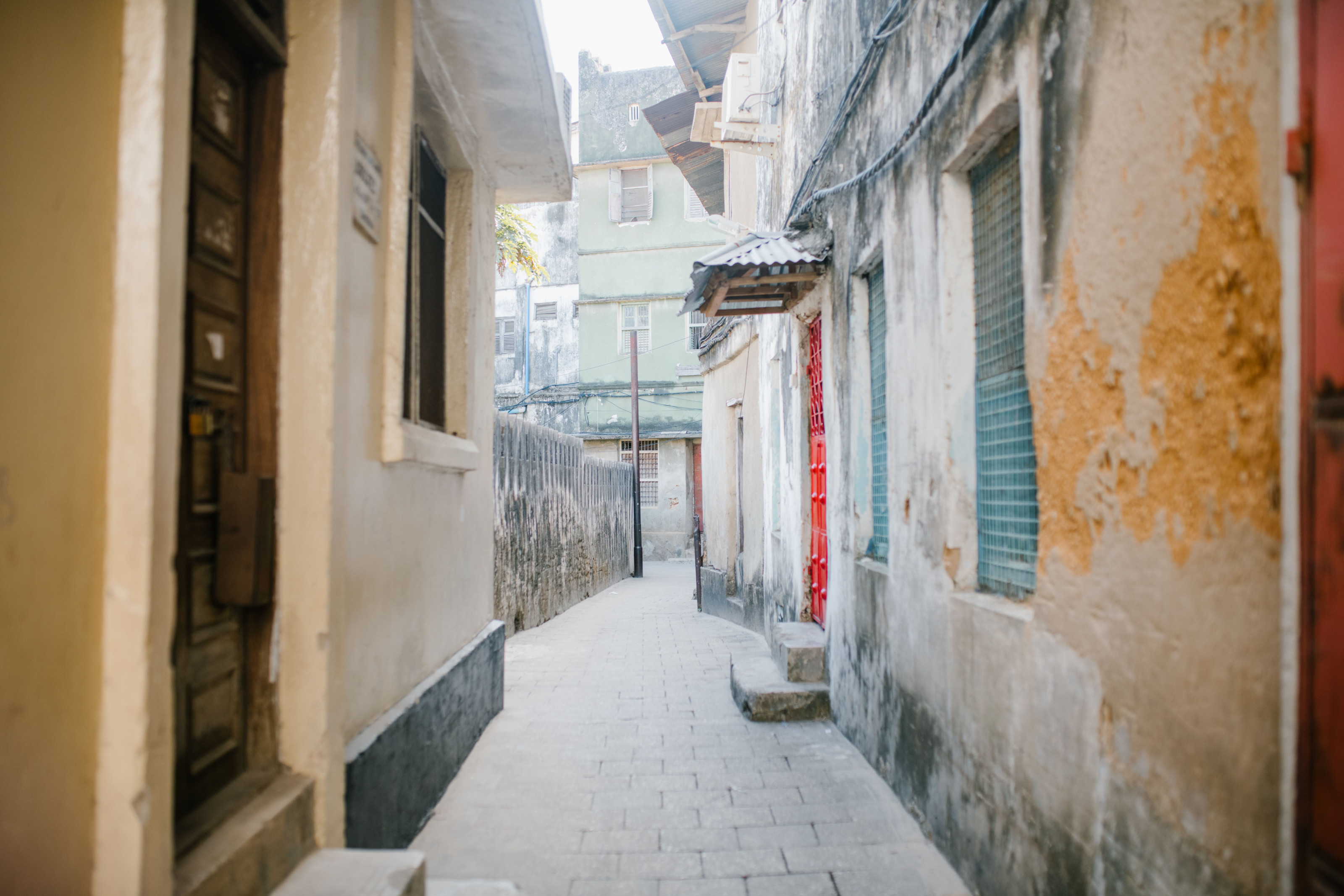 A narrow paved alley running between weathered stone buildings.