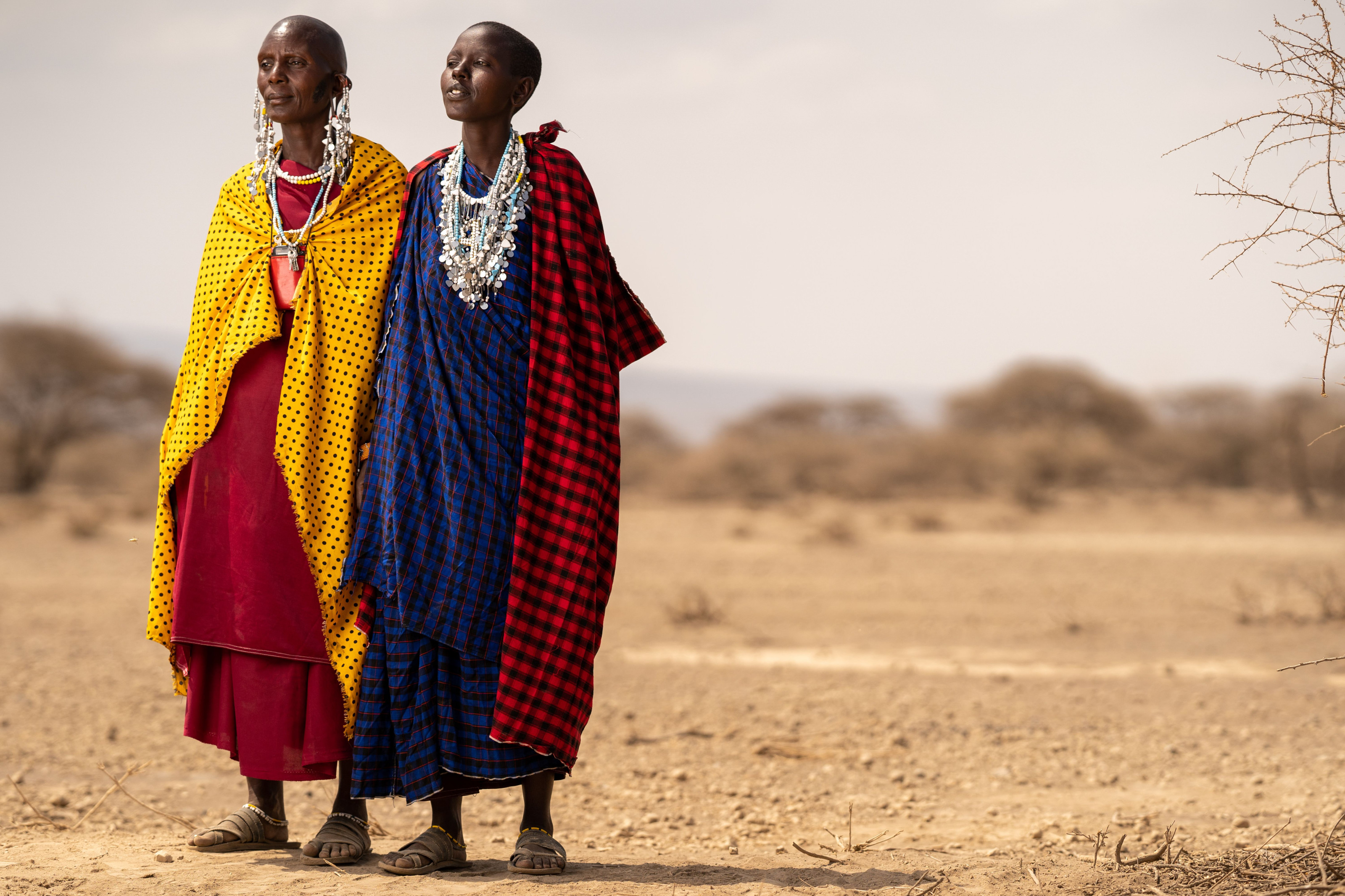 A group of people in checkered traditional robes standing together on open plains.