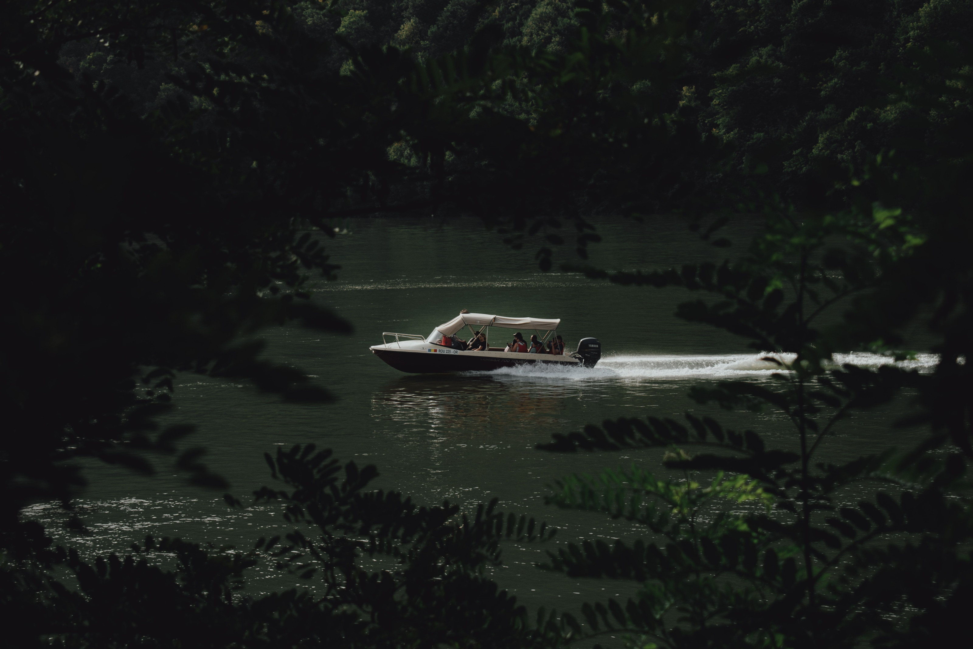 A small boat carries passengers along a river bordered by dense green forest.